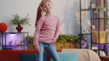 Evde yalnız başına müzik dinlerken kulaklıklı, dans eden ve zıplayan mutlu çocuk.