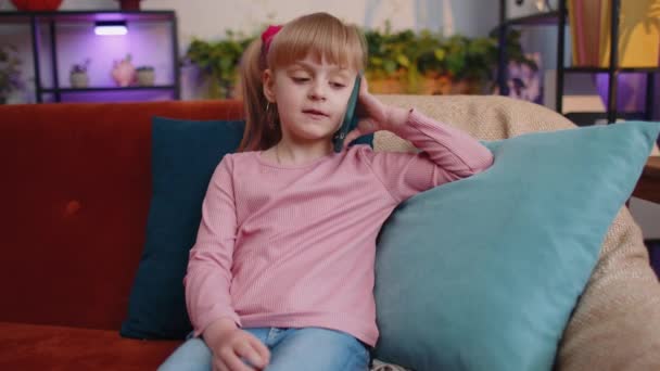 Meisje kind genieten van gesprek op mobiele telefoon met vriend ontspannen zitten op de bank alleen thuis — Stockvideo