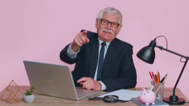 Kıdemli işadamı kameraya bakıp gülümsüyor, şanslı kazananı seçiyor, muhteşem olduğunu gösteriyor.