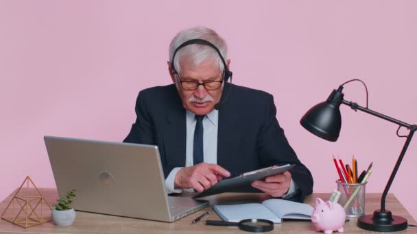 Senior businessman in headphones making conference video call on laptop, call center agent, operator — Stock Video