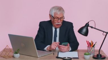 Mutlu kıdemli iş adamları akıllı telefon kullanır. Büyük kazanç. Ani zaferle şok olan iyi haber.