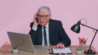 Öfkeli kıdemli iş adamı Pembe Ofis 'te telefonla konuşuyor.