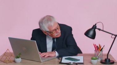 Endişeli kıdemli işadamı iş yerinde oturup çalışmaktan ve yarışmaktan veya video oyunlarından kaçınıyor