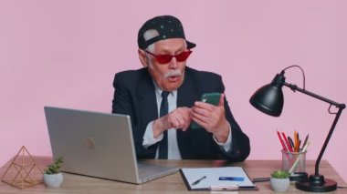 Mutlu kıdemli iş adamları akıllı telefon kullanır. Büyük kazanç. Ani zaferle şok olan iyi haber.