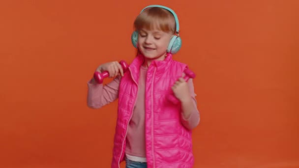 Cheerful attractive girl listening music via headphones and dancing disco fooling around having fun — Stock Video
