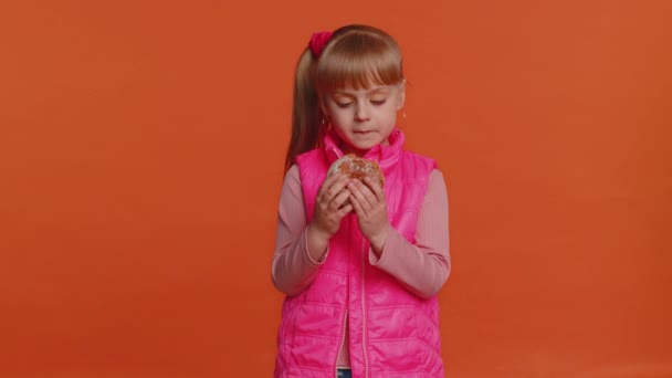 Возбужденный ребенок ребенок девочка ест вкусный пончик быстрого питания пончик торт, сахар глюкозы, сладкий нежелательной концепции — стоковое видео