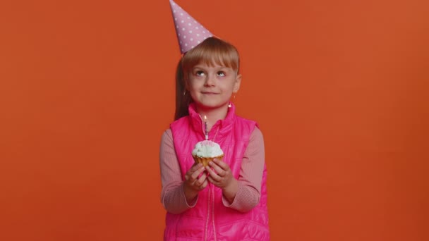 Boldog kisgyermek lány ünnepli születésnapi party, fúj gyertya a kis torta — Stock videók