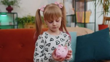 Frustrated poor little kid girl hold almost empty piggybank with only one dollar cash, bankruptcy