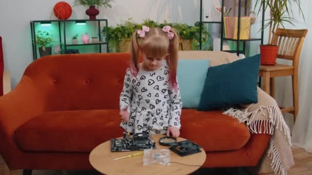 Little girl kid fixing repairing computer mainboard technology part, using magnifying glass at home — Video Stock