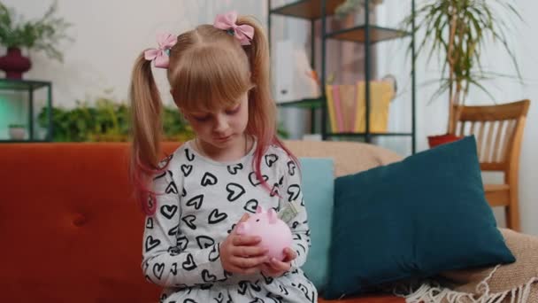 Frustrated poor little kid girl hold empty money piggybank with one dollar cash, poverty, bankruptcy — Wideo stockowe