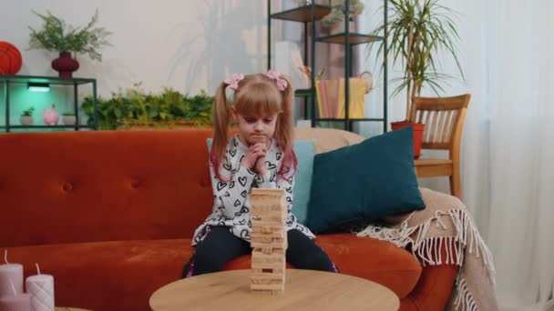 面白いです小さな一人のティーン子供女の子遊びます木製タワーブロックレンガゲームで自宅で現代的なリビングルーム — ストック動画