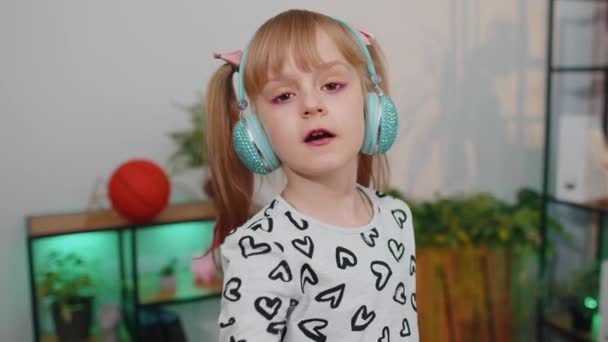 Enfant heureux fille enfant dans les écouteurs danser et sauter tout en écoutant la musique à la maison seul — Video