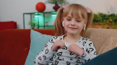 Küçük çocuk kanepede dinleniyor, kablosuz kulaklık takıyor, müzik dinliyor, en sevdiği şarkıyı dinliyor.