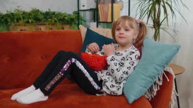 Shocked children girl watching comedy video tv program or movie film content on tv, eating popcorn