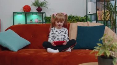 Endişeli genç kız çocuk evde akıllı telefondan video oyunu oynuyor.