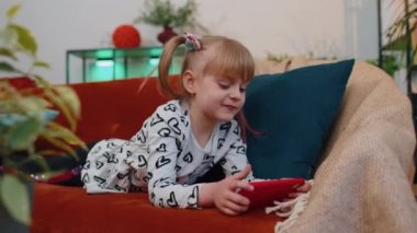 Endişeli genç kız çocuk evde akıllı telefondan online yarış oyunları oynuyor.
