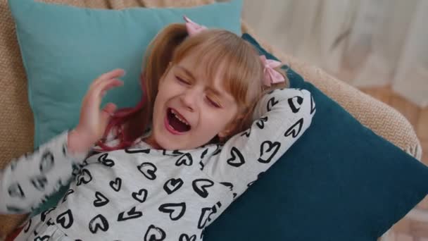 Маленька дівчинка-підліток, яка спить, позіхає, насолоджується безтурботними мирними вихідними, на дивані вдома — стокове відео