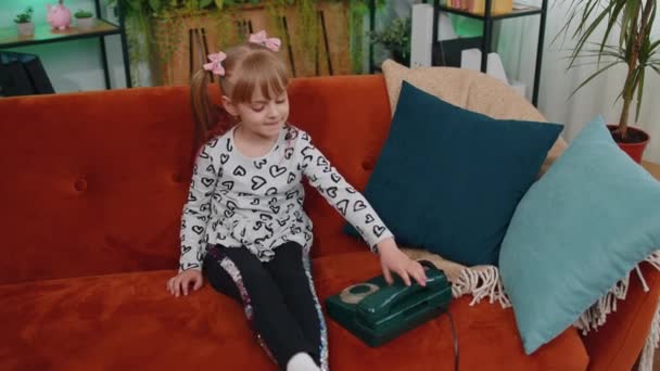 Smiling young children girl making conversation call on retro phone with friends on couch at home — 비디오