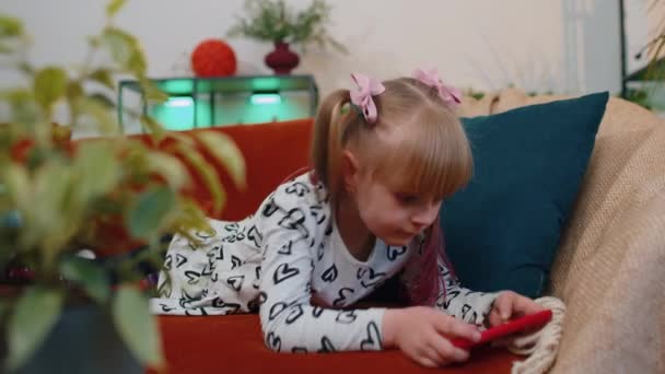Worried teen child girl kid enthusiastically playing shooter video online game on smartphone at home — Stock video