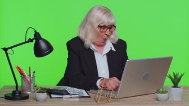 Kıdemli iş kadını mali tabloları analiz ediyor. Ev işyeri masasında kazanılan başarıyı kutluyor.