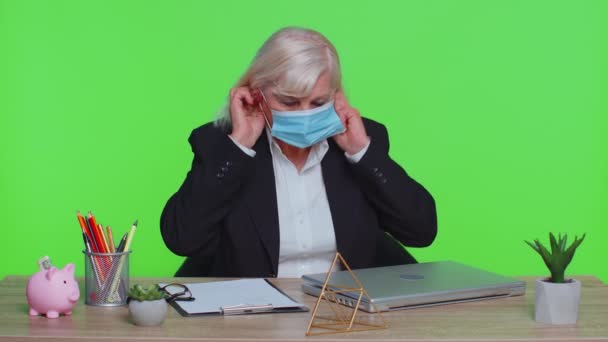 Sad unhappy senior office businesswoman putting on face medical mask, prevent respiratory infection — Stock Video