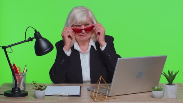 Mulher de negócios elegante sênior usa óculos de sol vermelhos, olhando para a câmera, piscando piscando olhos flertando — Vídeo de Stock