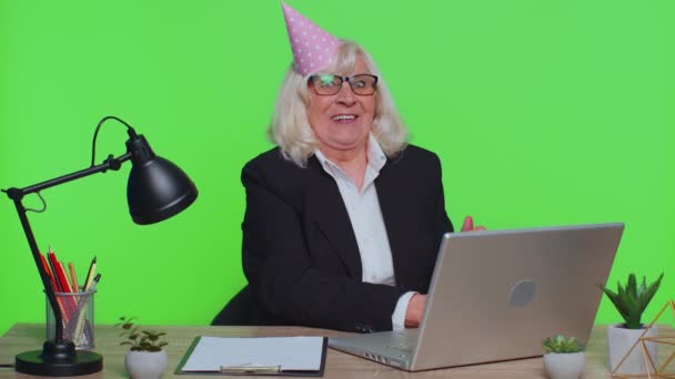 Femme d'affaires senior célébrant anniversaire solitaire dans le bureau soufflant bougie sur petit gâteau faire un souhait — Video