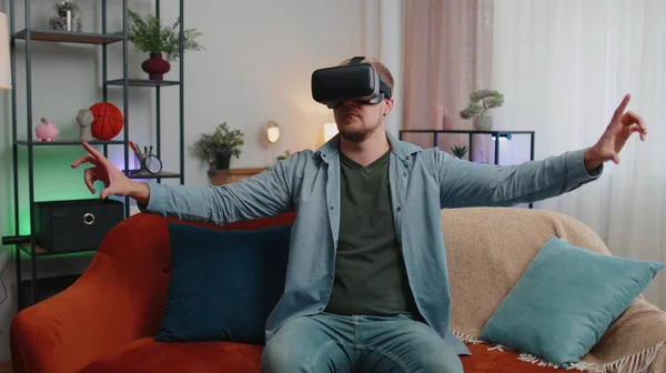 Hombre adulto utilizar gafas de realidad virtual auriculares en casa, disfrutando de vídeo concepto de mover las manos en el aire —  Fotos de Stock