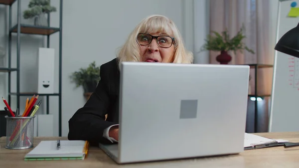 Senior mature older business woman hiding behind laptop computer, making funny face, fooling around — Stock Photo, Image
