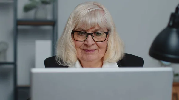 Senior businesswoman wears glasses working at home office, online webinar using laptop computer — Stock Photo, Image