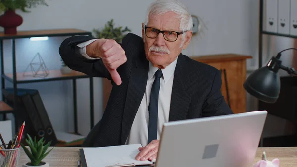 Upset senior business man showing thumbs down sign gesture, disapproval, dissatisfied, dislike