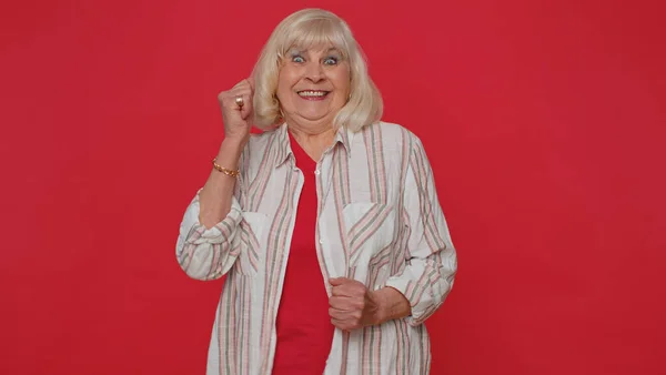 Stylish senior old woman shouting, raising fists in gesture I did it, celebrating success winning — Stockfoto