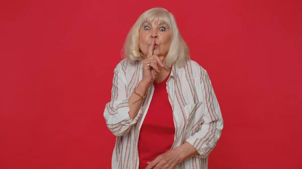 Seniorenvrouw drukt op wijsvinger tegen lippen maakt stiltegebaar vertelt geen geheim, stil zijn — Stockfoto