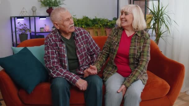 快乐快乐的老年人家庭夫妇祖父母有愉快的爱情对话的男人女人 老祖母爷爷彼此交谈 坐在家里的沙发上 — 图库视频影像