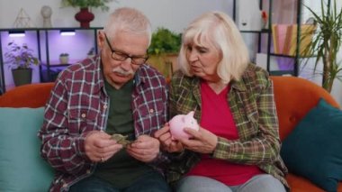 Zavallı yaşlı yaşlı aile büyükbabası ve büyükannesi evdeki domuz kumbarasından para sayan erkek kadın. Olgun büyükbaba son bir doları elinde tutuyor. Yoksulluk borcu finansal sorun, emeklilik