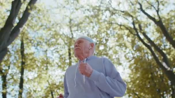 Motywowana siłownia atletyczna emerytowany starzec biegający w parku, dziadek zdrowy sport aktywny — Wideo stockowe