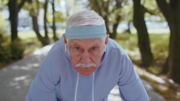 Starszy sportowiec mężczyzna dziadek działa jogging w słonecznym parku podczas porannego treningu cardio na świeżym powietrzu — Wideo stockowe