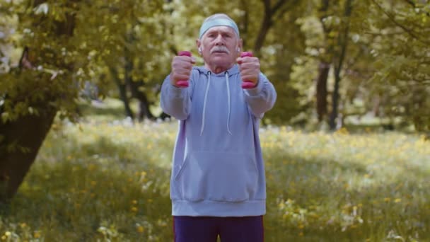 Homme âgé faisant de l'exercice, faisant haltère exercices de levage de poids, pratiquant l'entraînement sportif dans le parc — Video