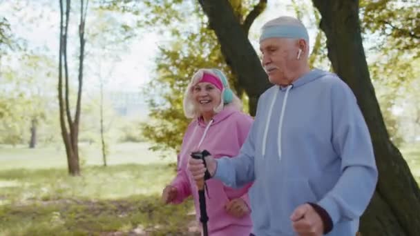 Wesoły starszy para dziadek, babcia trening nordic walking, bieganie w letnim parku — Wideo stockowe