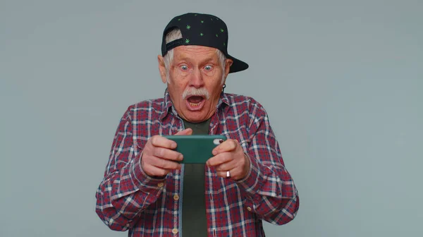 Preoccupato divertente dipendente uomo anziano entusiasticamente giocare drive racing videogiochi sul telefono cellulare — Foto Stock