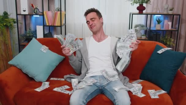 一个成功的有钱的生意人 带着高利贷 彩票游戏赢了 满足了财富收入的薪水 在家里的沙发上躺着满满的美元钞票 — 图库视频影像