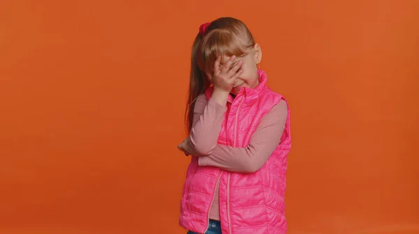 厌烦的女孩穿着粉红背心做鬼脸的手势 感到厌烦 对工作的结果感到失望 坏消息 年幼的孩子失望了 孤身一人孤身一人躺在橙色工作室的背景下 — 图库照片
