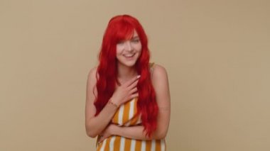 Komik anekdot, komik fıkra dinledikten sonra gülen neşeli kızıl saçlı kadın kaygısız, neşeli, pozitif insanların yaşam tarzını hisseder. Genç kızıl kız bej renkli stüdyo arka planında tek başına izole edilmiş.