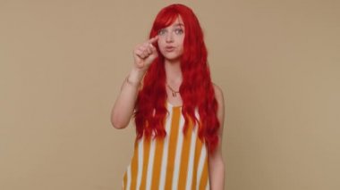 Hey sen! Kolsuz tişörtlü kızıl saçlı kadın heyecanla gülümsüyor ve kamerayı işaret ediyor, şanslı piyango talihlisini seçiyor, bu da seni harika gösteriyor. Genç kızıl saçlı kız bej renkli stüdyo duvarında tek başına izole edilmiş.