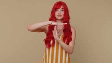 Uzun kollu tişörtlü, sinirli bir kadın mola, sınır, mola tabelası gösteriyor, baskı yok, zamana ihtiyacım var. Genç kızıl saçlı kız bej renkli stüdyo duvarında tek başına izole edilmiş.