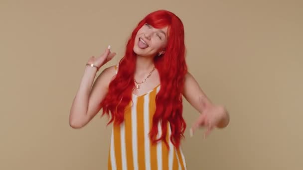 Funny joyful sincere redhead woman 20s in tank top making playful silly facial expressions and grimacing, fooling around showing tongue. Young beautiful ginger girl isolated alone on beige background — Stock Footage Funny Joyful Sincere Redhead Woman 20S Tank Top Making Playful Stock Footage