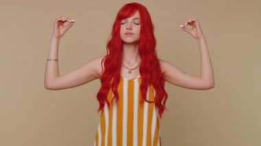 Sakin ol, rahatla, iç denge. Kadın derin nefes alıyor. Mudra jesti, gözleri kapalı. Yoğun düşüncelerle meditasyon yapıyor. Kızıl saçlı yetişkin kız bej renkli stüdyo arka planında izole edilmiş.