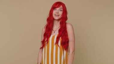 Sevimli, neşeli kızıl kadın önerini çok beğeniyor. Başını sallıyor, güzel bir işten memnun, evlenme teklifi gibi. Zencefilli genç kız bej renkli stüdyo arka planında izole edilmiş.