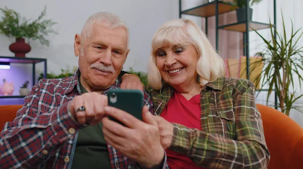 Oh my God Wow. Amazed senior mature family couple grandparents man woman use mobile smartphone, receive good news message, shocked by sudden victory, celebrate win, purchases online shopping at home