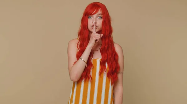 请安静 红头发女人的肖像20多岁按食指到嘴唇使沉默手势不泄密 年轻美丽的姜姑娘在米色工作室的背景下摆出孤立无援的姿势 — 图库照片